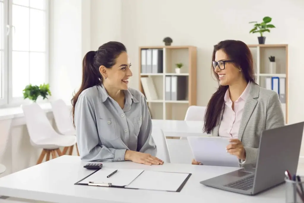 Two business professionals discussing transactions and utilizing POS features on a laptop in a modern office.